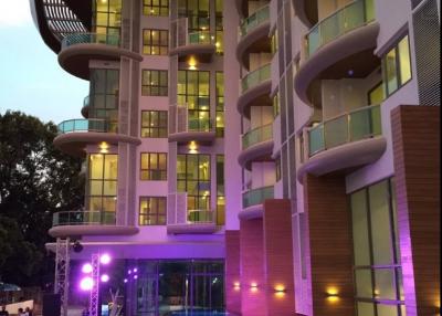 Modern apartment building with illuminated balcony features and pool area during twilight