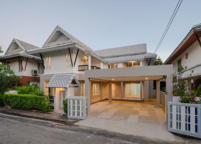 Spacious suburban house with a covered carport and lit interior at dusk