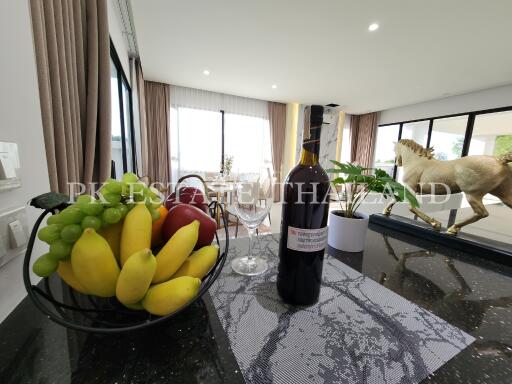 Modern kitchen with a fruit bowl and wine on the countertop, overlooking a spacious living area