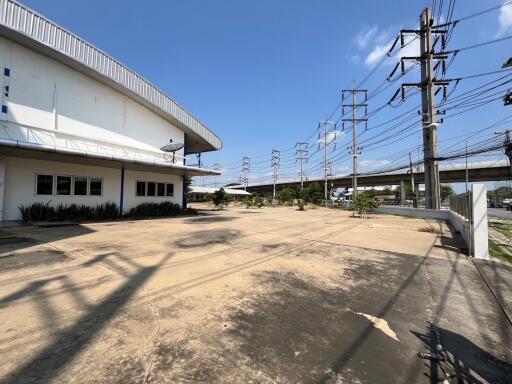 Spacious parking area outside a large industrial building with clear skies