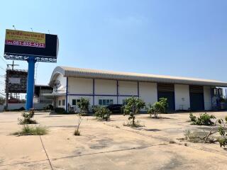Spacious commercial warehouse exterior with large parking area under a clear blue sky
