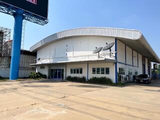 Exterior view of a modern industrial building with satellite dishes and clear blue sky