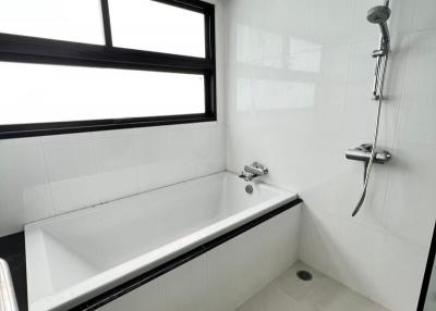 Modern bathroom interior with a clean bathtub, handheld showerhead, and large window