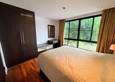 Spacious bedroom with hardwood floors and large window