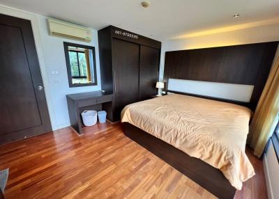 Spacious bedroom with large bed, wooden flooring, and modern furniture