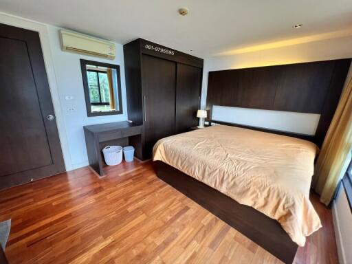 Spacious bedroom with large bed, wooden flooring, and modern furniture