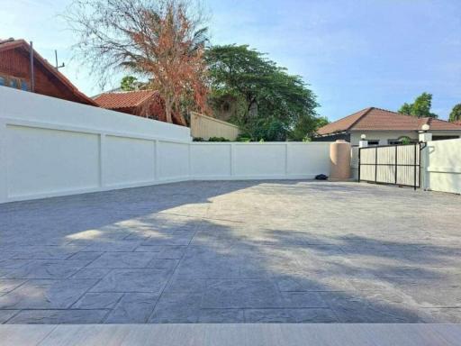 Spacious outdoor paved patio area with a high surrounding wall