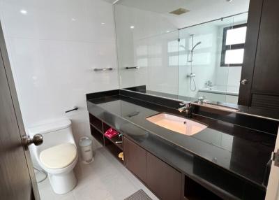 Modern bathroom interior with glass shower, large mirror, and dark wood vanity