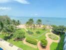 View from balcony overlooking the sea, palm trees, and landscaped garden