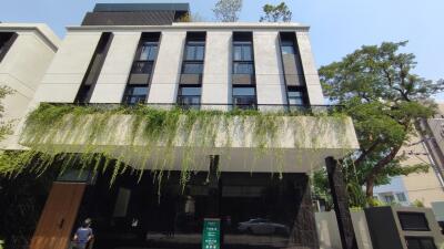 Modern multi-story residential building facade with hanging green plants