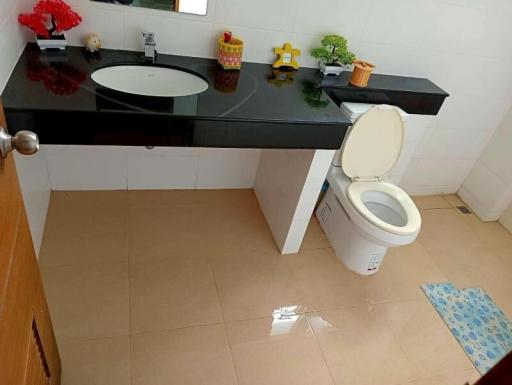 Modern bathroom with glossy floor tiles, black countertop, and white fixtures