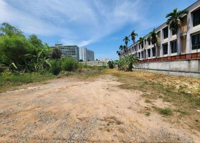 Empty land plot with surrounding buildings under a clear blue sky