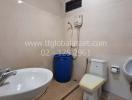 Compact bathroom with wall-mounted sink, toilet, and bidet