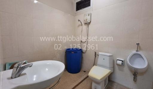 Compact bathroom with wall-mounted sink, toilet, and bidet