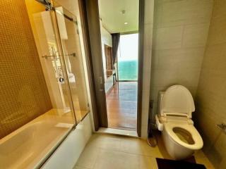 Modern bathroom with a glass shower cubicle, toilet, and access to balcony with ocean view