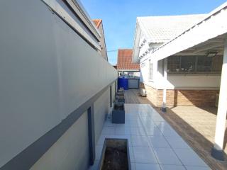 Exterior view of a building showcasing the side pathway, drainage, and tiled flooring