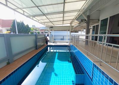 Outdoor swimming pool with protective roofing and surrounding terrace