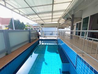 Outdoor swimming pool with protective roofing and surrounding terrace