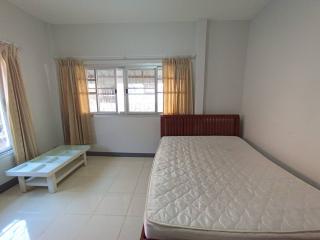 Spacious bedroom with a large window, queen-sized bed, light curtains, and a coffee table