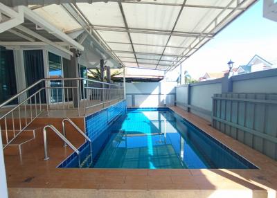 Swimming pool area with protective railing and ample deck space outside a residence