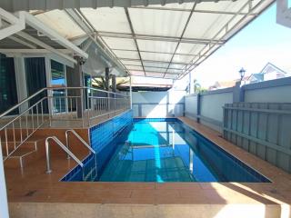 Swimming pool area with protective railing and ample deck space outside a residence