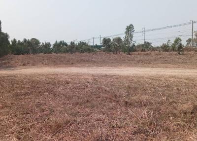 Empty land with dry grass and trees in the background near a rail line
