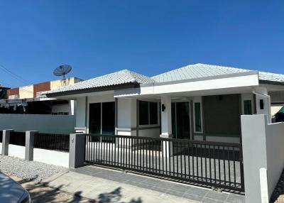 Single-story residential home with grey roofing and fenced front patio under a clear blue sky