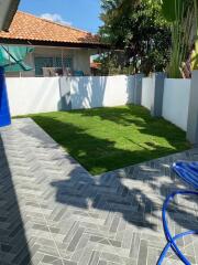 Spacious Backyard with Green Lawn and Tiled Patio Area