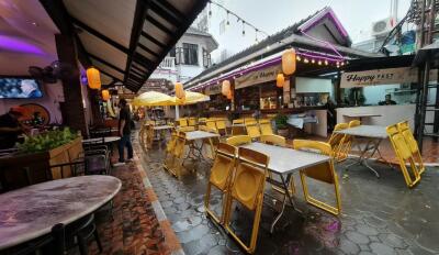 Café outdoor dining area with yellow chairs and festive lighting