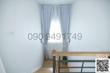 Bright hallway in residential building with wooden banister and stairway