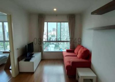 Cozy living room with wooden flooring, red sofa, and city view