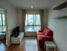 Cozy living room with wooden flooring, red sofa, and city view