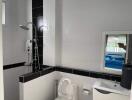 Modern bathroom with white and black tiles, shower, and toilet