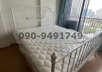 Well-lit bedroom with white metal bed frame and mattress