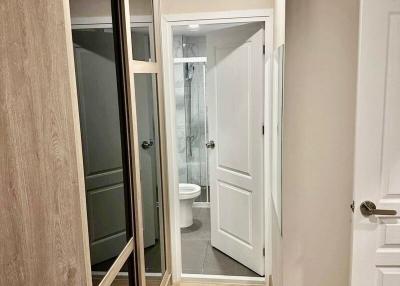 Corridor leading to a modern bathroom with glass shower door
