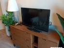 Flat screen TV on a wooden stand with drawers in a living room accompanied by a floor lamp and green plant