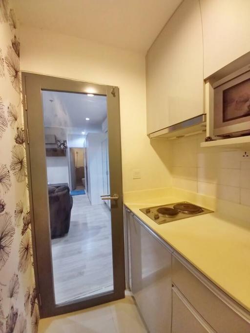 Compact kitchen with white cabinetry and a view into the corridor