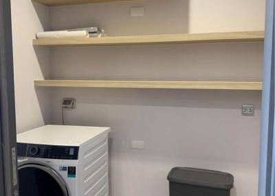Compact laundry room with washing machine and storage shelves