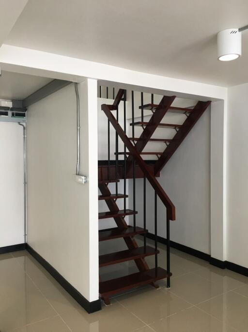 Modern staircase with dark wooden steps and metal railings inside a well-lit space