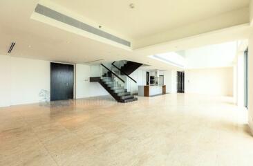 Spacious open-plan living area with large staircase and natural lighting