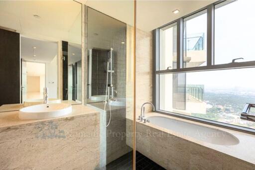 Modern bathroom with natural light, featuring a bathtub and glass shower