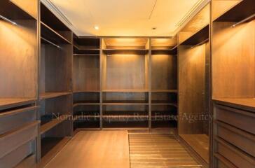 Spacious walk-in closet with wooden shelves and cabinets