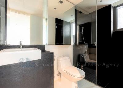 Modern bathroom with white fixtures and dark tiling