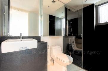 Modern bathroom with white fixtures and dark tiling