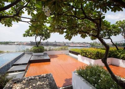 Spacious terrace with a view of the river, featuring a swimming pool and surrounded by lush greenery