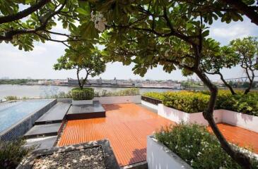 Spacious terrace with a view of the river, featuring a swimming pool and surrounded by lush greenery