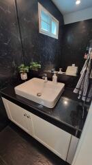 Modern bathroom with black marble walls and a white vanity