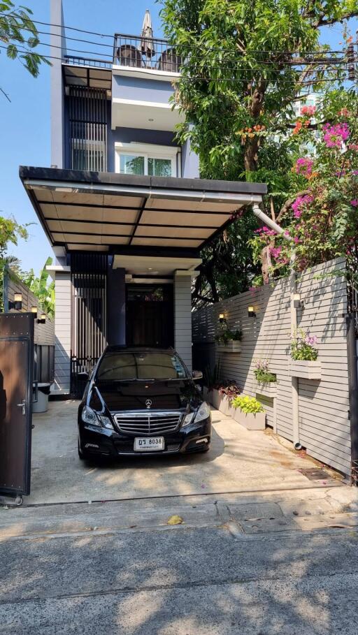 Modern three-story house with carport and lush landscaping