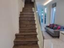 Modern staircase with glass railing, wooden steps, and polished floor leading to the upper level of a home