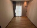 Spacious unfurnished bedroom with wooden flooring and ample natural light